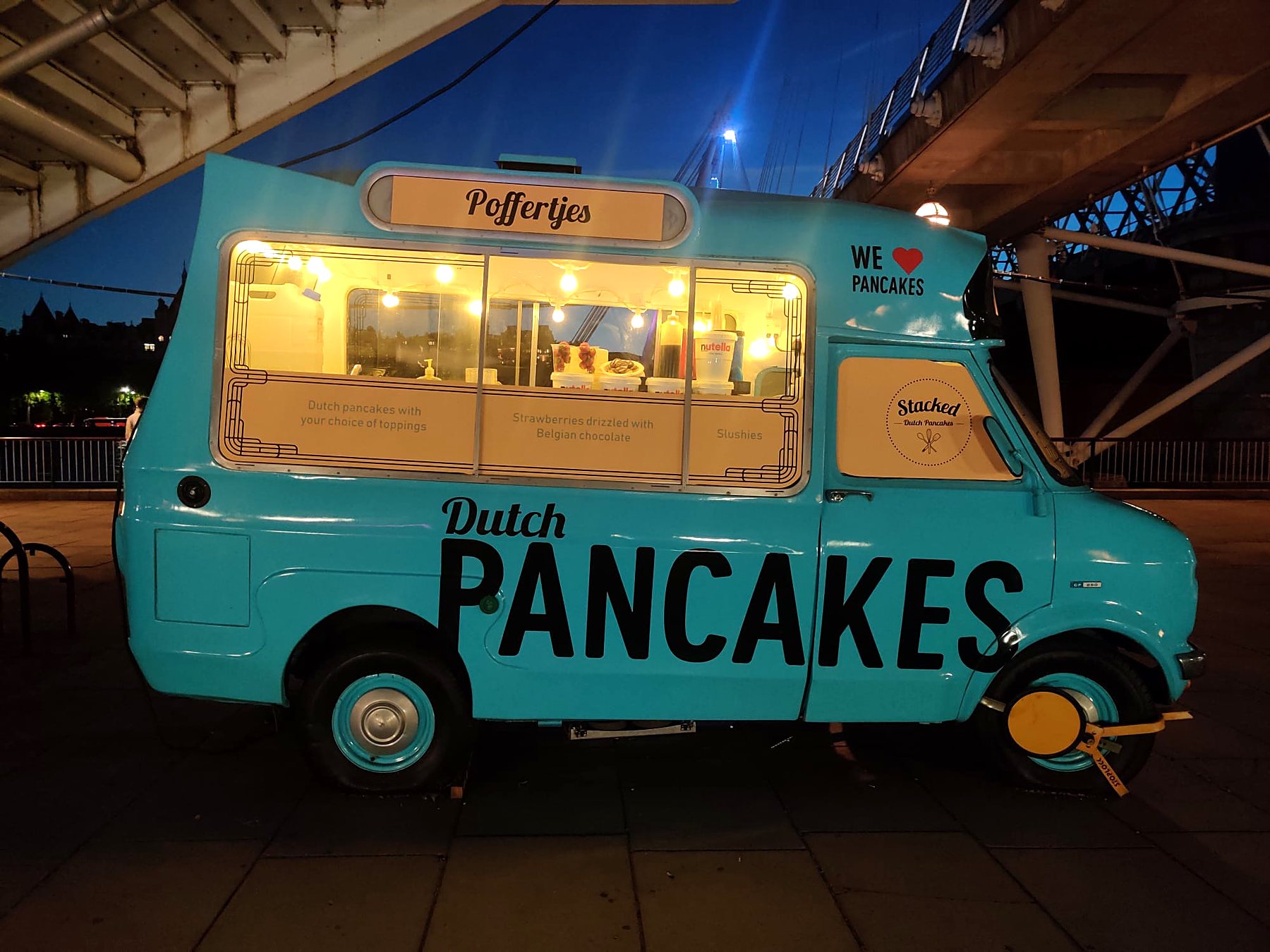 Stacked's vintage blue Dutch pancake van lit up at dusk on London's Southbank